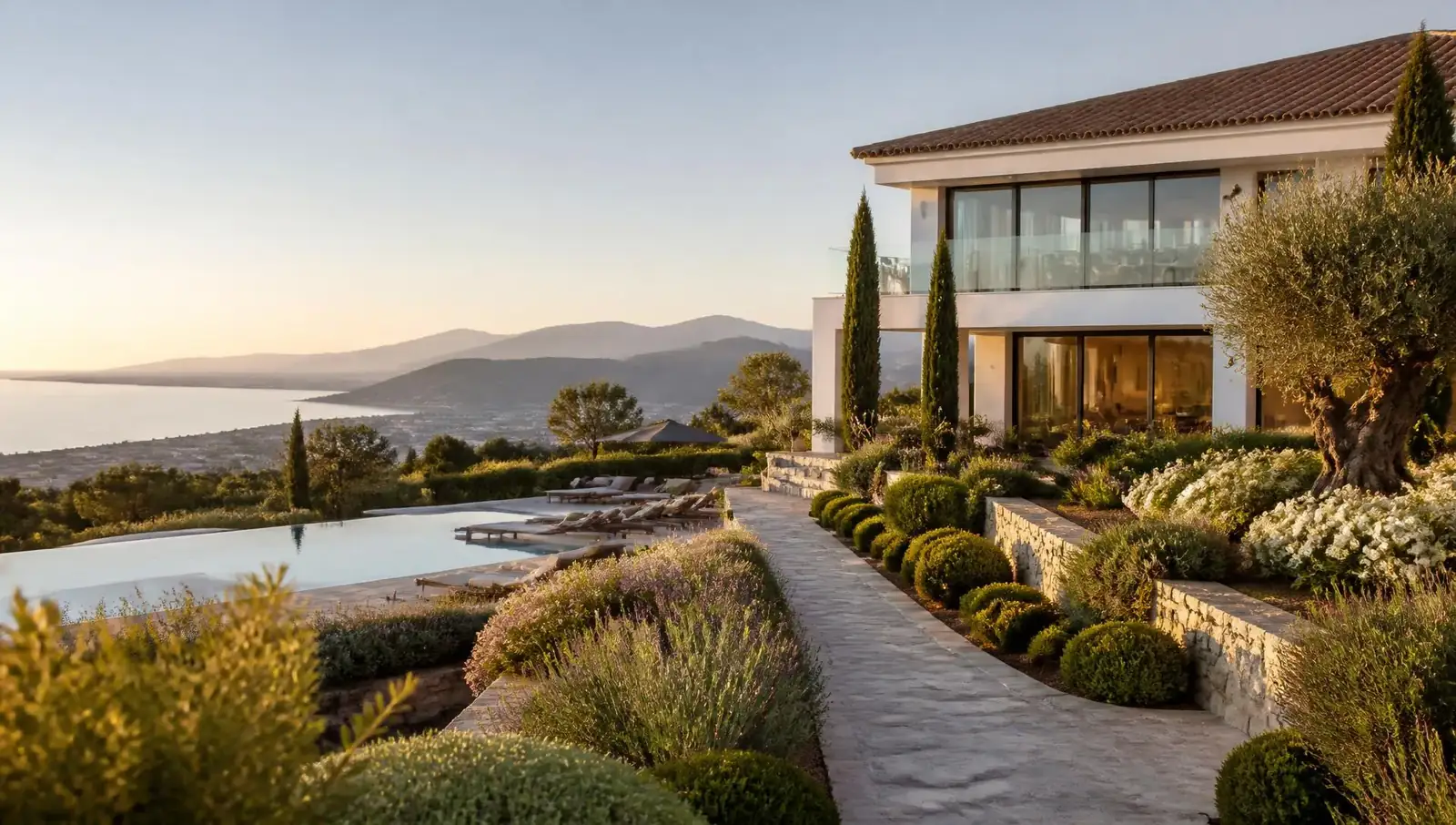 Villa de lujo en la Costa del Sol con jardín mediterráneo cuidado, cipreses, olivos y piscina al atardecer